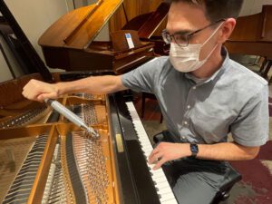 Photo of technician working on piano strings
