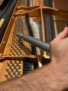 Photo of hand tuning a piano's strings