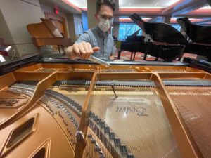 Photo of tuner looking at a piano's strings