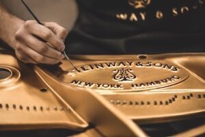 A Steinway craftsman handpainting the company logo