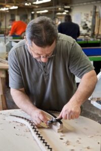 Steinway craftsperson working on a piano soundboard.