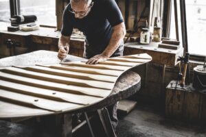 Steinway craftsman working on a grand piano soundboard.